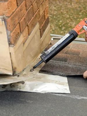 Chimney flashing repair project in New Jersey during clear weather with close-up of sealant application Chimney flashing repair project in New Jersey during clear weather with close-up of sealant application