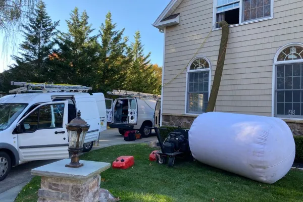 Residential dryer vent cleaning service in progress at a home with equipment set up outside
